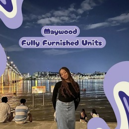 a woman smiling outdoors beside a bridge