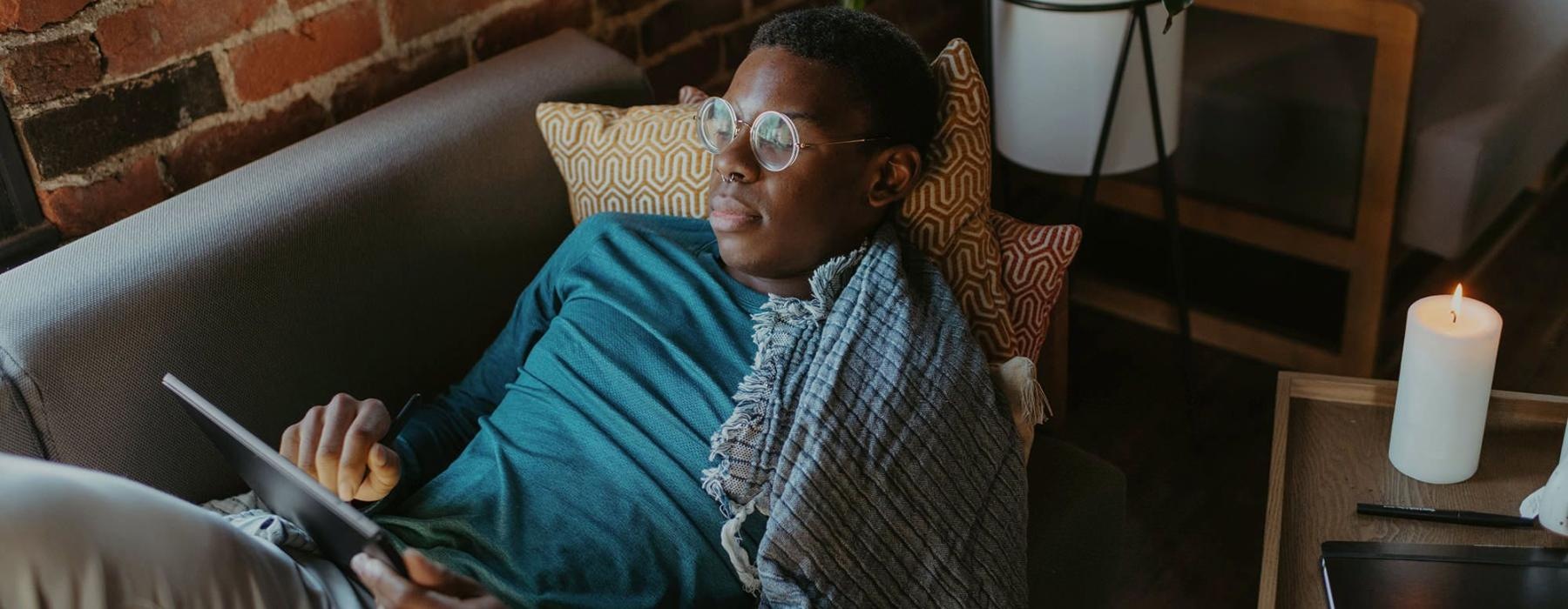 a man looks at his tablet while lying on his living room couch